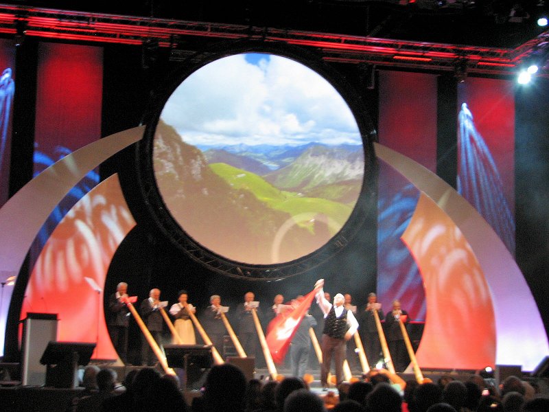 IMG_2707.jpg - Entertainment at the Opening of course included the sounds of the 'Alps horn' … in fact eleven of them along with a colorful twirling, tossing Swiss flag presentation.  Easy? Oh yeah?  You try it.  The Alps horns and about 12-15 feet long and comes in three sections for easy (?) handling.  Remember Heidi?  Nice.