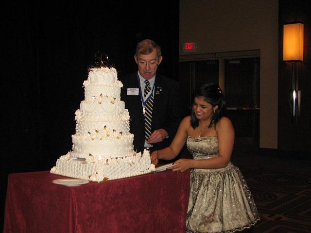 IMG_6472.JPG - It’s a BIRTHDAY PARTY!   Capital District CKI is celebrating its 50th Anniversary!   It can’t be done with much more style than I can think of:  KI President at the party and a BIG five layer white frosted cake.  Governor’s Don and Avanti cut the cake with flashing cameras.  Then pieces of Chocolate cake were passed out to all.  It was good, but what happened to the big white cake? I told them I thought it was taken from a wedding party and after the cutting ceremony we had to get it back … quickly!